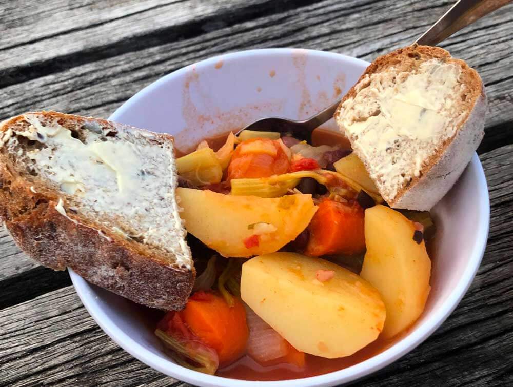 camp oven vegetable stew served in a bowl with bread